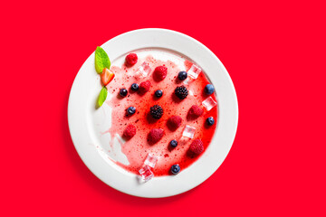 Strawberries and blackberries on defrosted popsicle over a red background