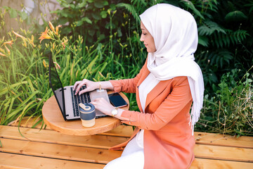 Beautiful young arabic girl in hijab working at street cafe.
