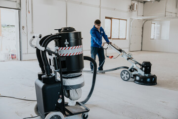 Worker using concrete milling machine, preparing floor © Doralin