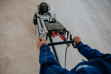 Worker using concrete milling machine, preparing floor © Doralin