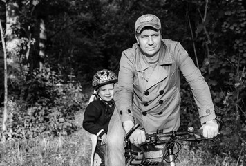 Bicycle ride of father and his son on baby seat.