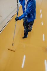 A construction worker apply epoxy resin in an industrial hall