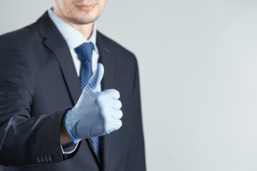 A businessman in rubber gloves gives a thumbs up. Crop photo with copy space. The concept of removing restrictions post-pandemic.