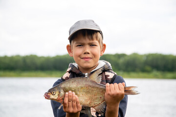 seven year old boy holds a fish he caught
