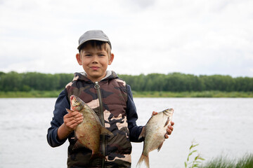 seven year old boy holds a fish he caught