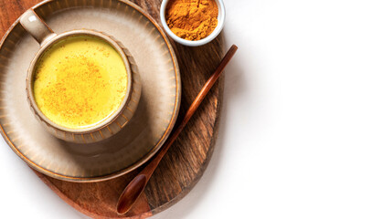 Tasty healthy drink made from turmeric, milk and spices in a mug on a white background top view, free space for text. Golden milk. Latte made from milk and turmeric. Detox drink.
