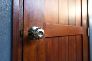 Close-up on brass metallic knob of wooden door, selected focus on the key hole. Interior house equipment object.