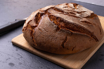 round single loan of brown bread on the stone concrete dark grey background