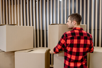 young man courier is arranging the cardboard boxes parcels and waiting to be shipped