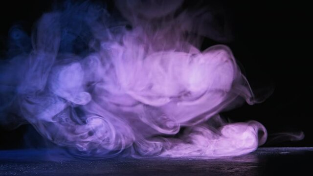 Color smoke swirl. Mystic power. Vapor puff motion in neon pink blue light on black background.