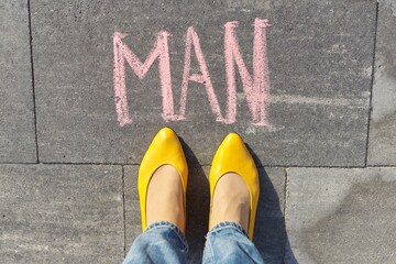 Man concept, top view on woman legs and text written in chalk on gray sidewalk