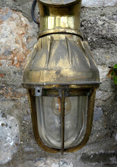 A brass wall lamp on a stone wall.