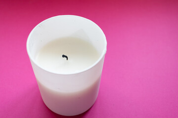 Close up of white candle on a pink background. Copy space