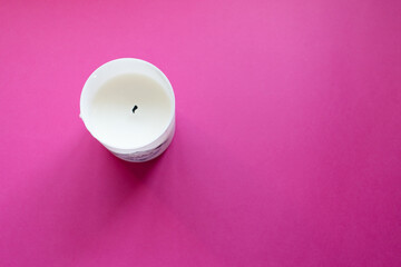 Close up of white candle on a pink background. Copy space