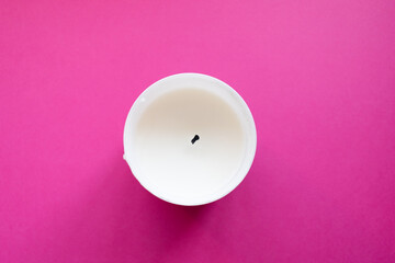 Close up of white candle on a pink background. Copy space