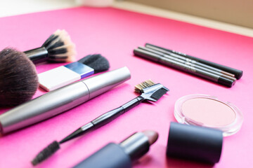 Obraz na płótnie Canvas Make up products, brushes, lipstick, eyeliner on a pink background. Beauty concept