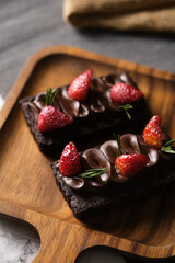 Rectangular chocolate tart with strawberry set in cafe table.