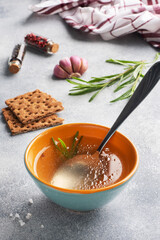 Boiled meat broth in a plate with spices garlic and rosemary.