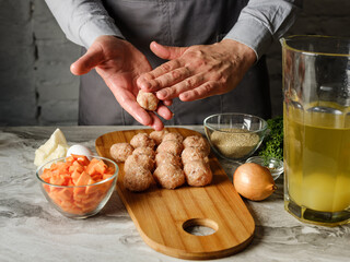 Meatball cutlet cooking by homemade recipe with farm meat, organic vegetables, herbs and spices by man cook hands on kitchen background
