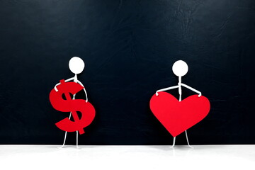 Human stick figures holding a red heart shape and a dollar sign. Money versus love, family or...