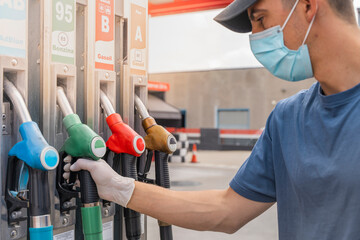 Coronavirus. Car refueling on petrol station. Man with face mask pumping gasoline oil during...
