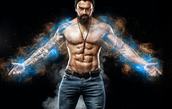 Athlete bodybuilder in blue energy lights. Handsome fit man posing wearing in jeans with tattoo. Sport and fashion concept isolated on black background.
