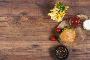Fast food burger menu, french fries and ketchup sauce on wooden background.
