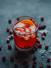 Aperol Spritz with ice and cranberries on a black background.