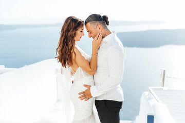 Wedding on Santorini island in Greece, beautiful couple, bride in a white wedding dress. White houses and blue sky