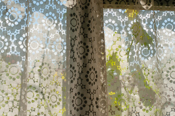 Old retro laced curtain on a wooden window on a rural house 