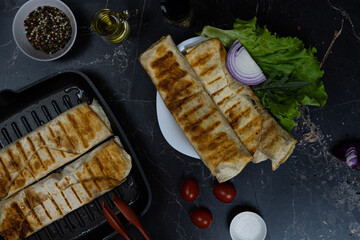 Grilled chicken Shawarma with spices and vegetables. Shawarma on a grill pan. Shawarma on a dark background. High quality photo