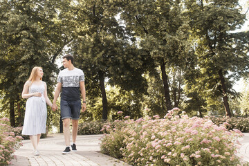 Fototapeta na wymiar Family together in the summer park. Woman is pregnant. Wife and husband are walking in the park. Man touch pregnant belly
