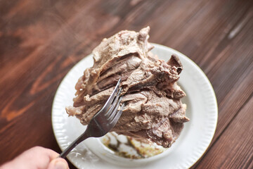 Cooked turkey meat on a fork on a wooden background.