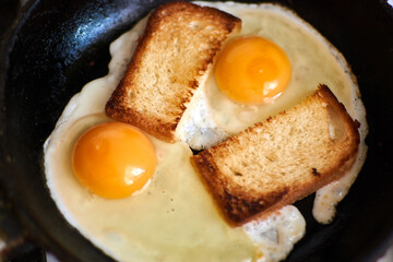 Two fried eggs with toast in a pan.
