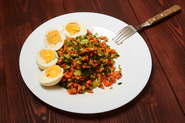 Salad of finely chopped vegetables - carrots, cabbage, cucumbers and boiled chicken eggs.