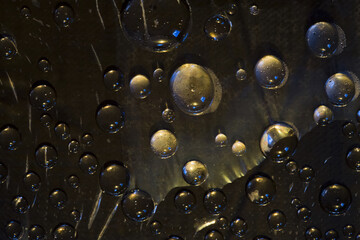 Black spheres are located on a black background and are lit by the yellow-blue light. Cosmic abstraction. 