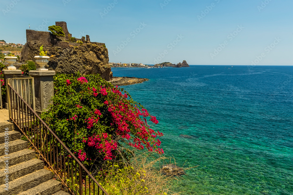 Wall mural a view across the seafront in acicastello, sicily looking towards the norman castle and the islets o