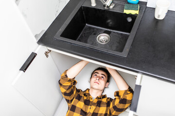 High angle view of male plumber repairing a sink in kitchen
