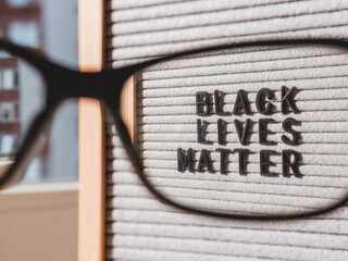 View on letterboard with words Black Lives Matter through eyeglasses. Concept with actual...