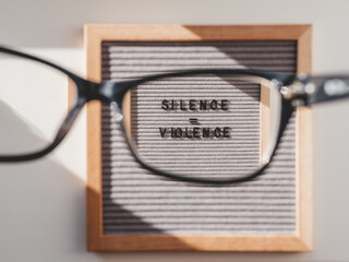 Top view on letter board with words Silence equal Violence through eyeglasses. Flat lay concept...