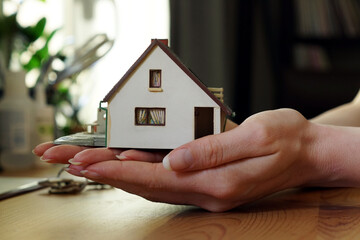 A person holding a miniature house - buying or selling a house concept
