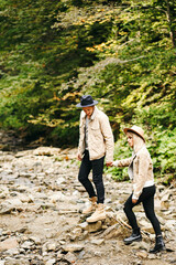 Young couple at the Carpathian - Happy tourists visiting mountains. Lovestory. Tourists in hats. Military fashion.