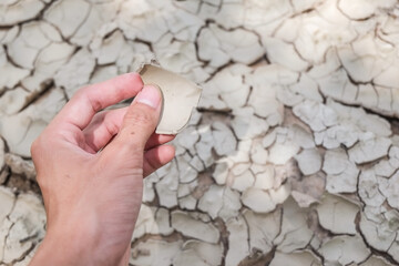 Piece of dry soil on the hand with blurred pattern dry ground soil field that is broken from...