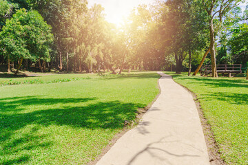 New pathway and beautiful trees track for running or walking and cycling relax in the park on green grass field on the side of the golf course. Sunlight and flare background concept.