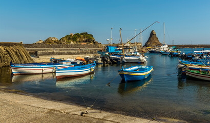 Fototapeta na wymiar Fishermen's boats against a background of Isole dei Ciclopi at Aci Trezza, Sicily in summer