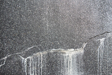 Close up Cracked wall on Shade of dark gray granite stone texture background, copy space. Cracking from water drop with white stain on black sand wash floor surface. Grunge & rough industrial wall