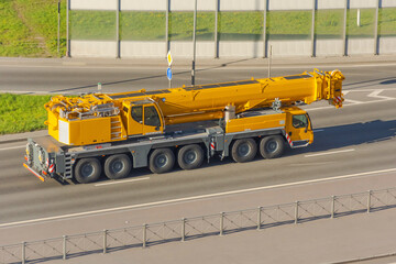Heavy mobile crane with folding boom construction rides on a city highway.
