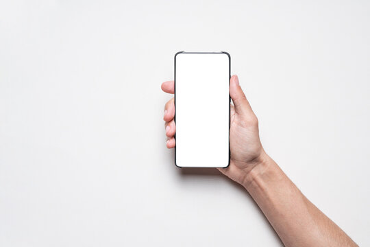 Smartphone mockup. Businessman holding phone with blank white screen on gray background. Template with copy space.