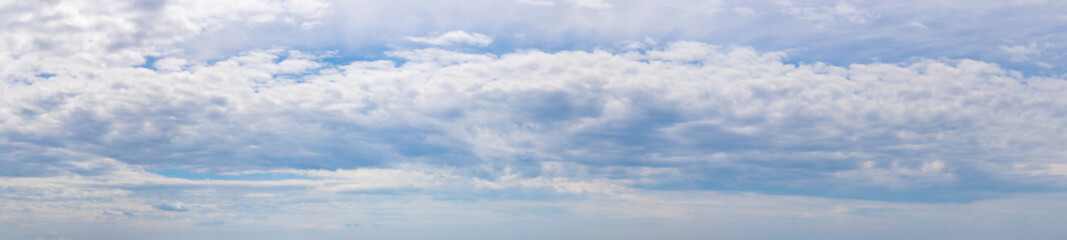 Panorama of blue sky with white clouds. Small white clouds stretch across the sky