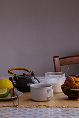 Taza de té negro con azúcar, limones y galletas en el fondo de la mesa rústica